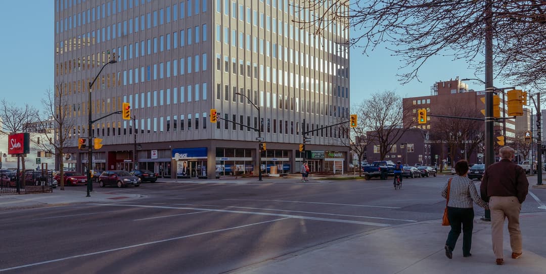 An active intersection in London Ontario with a cyclist, pedestrians, and cars.
